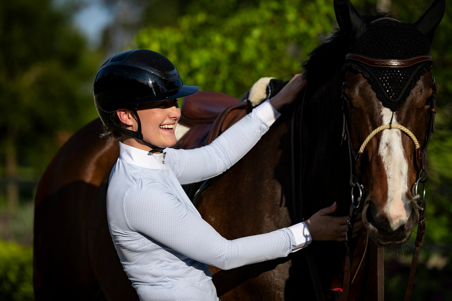 Rider in Wilma Sport Featherlight Competition Shirt in Misty Blue standing with a horse.