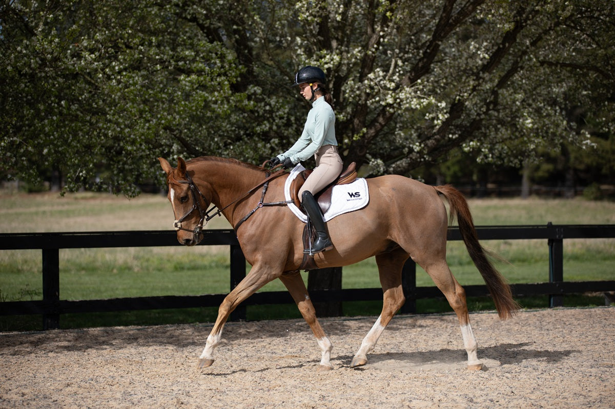 Model riding in Featherlight Training Shirt in Seafoam and Classic Hybrid Breeches in Urban Sand by Wilma Sport